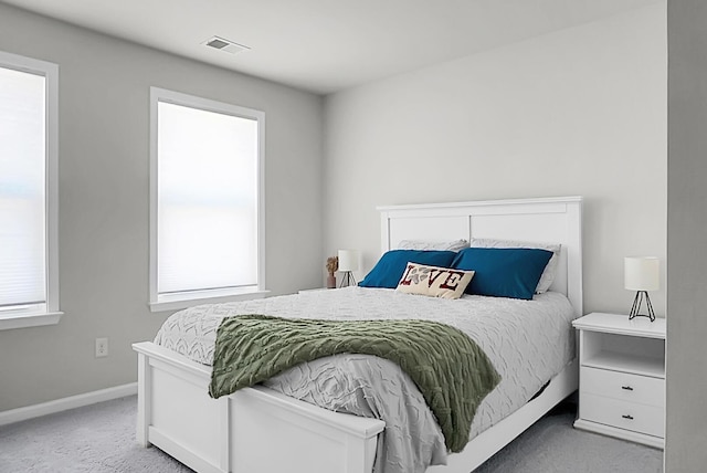 carpeted bedroom with multiple windows, visible vents, and baseboards