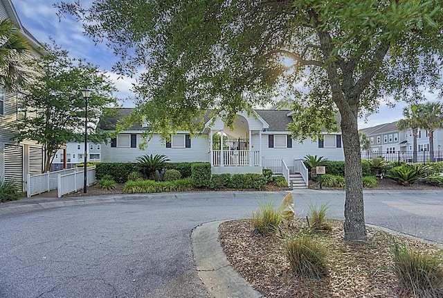 view of front of property with covered porch, fence, and a residential view