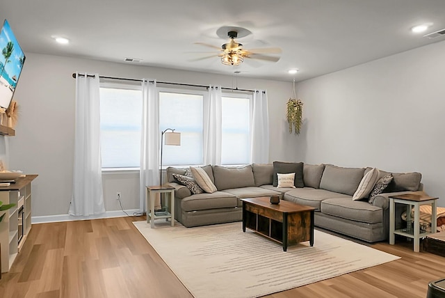 living area with ceiling fan, light wood finished floors, visible vents, and baseboards