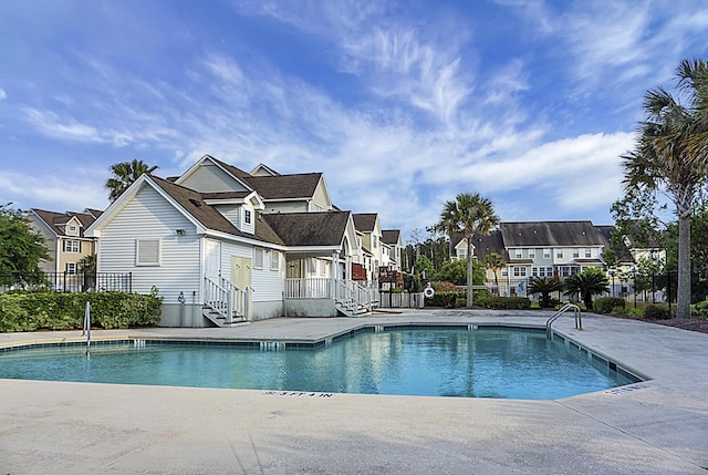 pool with a residential view, a patio area, and fence