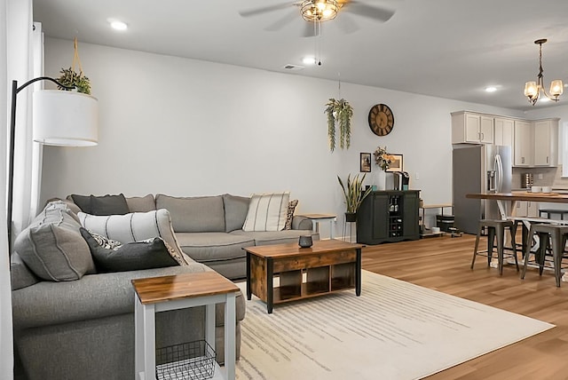 living area featuring recessed lighting, light wood-style flooring, visible vents, and ceiling fan with notable chandelier