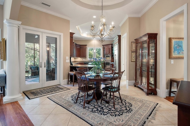 tiled dining space featuring a tray ceiling, french doors, a notable chandelier, and ornamental molding