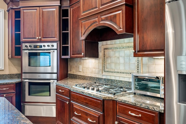 kitchen featuring dark stone counters, appliances with stainless steel finishes, and tasteful backsplash