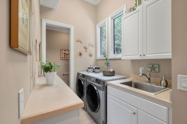 washroom with cabinets, light tile patterned floors, washer and clothes dryer, and sink