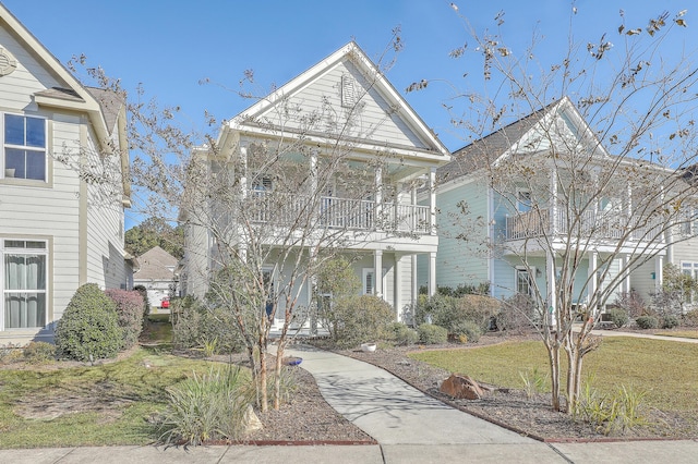 view of front of house with a balcony and a front lawn