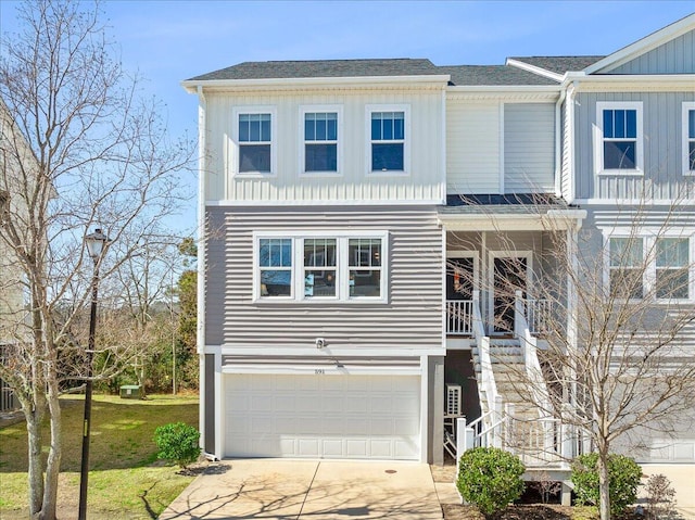 view of front of property featuring driveway, an attached garage, stairs, board and batten siding, and a front yard