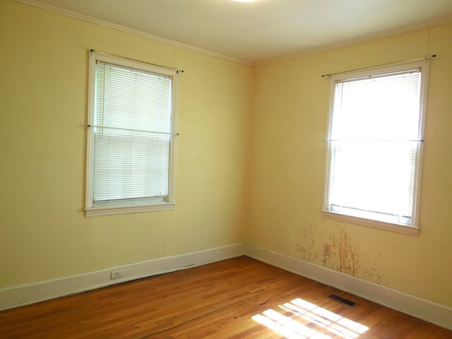 spare room with ornamental molding and light hardwood / wood-style flooring