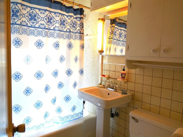 bathroom featuring decorative backsplash, tile walls, toilet, and plus walk in shower