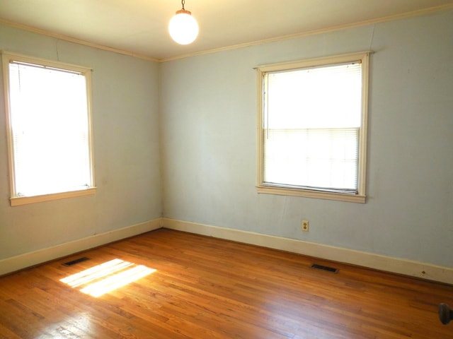 unfurnished room with plenty of natural light, ornamental molding, and wood-type flooring