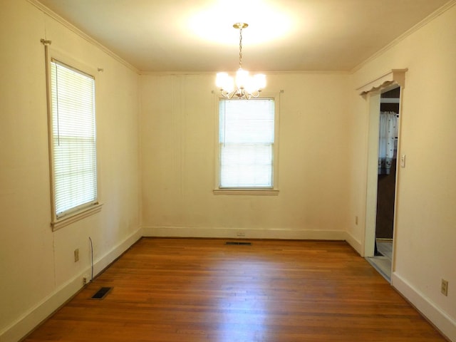 spare room with ornamental molding, hardwood / wood-style floors, and an inviting chandelier