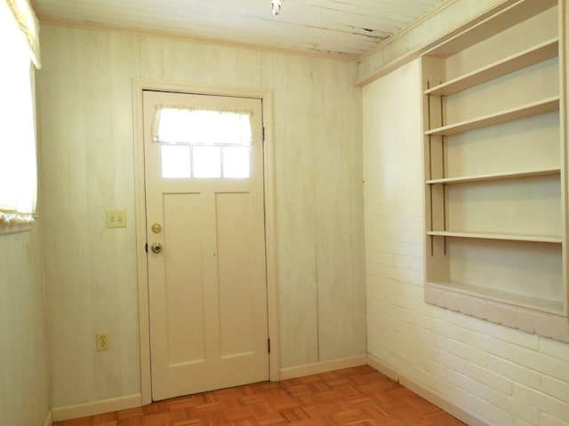 foyer entrance with brick wall, wood walls, light parquet flooring, and wooden ceiling