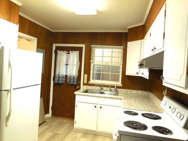 kitchen featuring white cabinets, wooden walls, sink, and white appliances