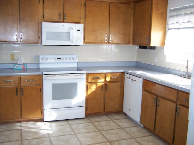 kitchen featuring decorative backsplash, sink, and white appliances