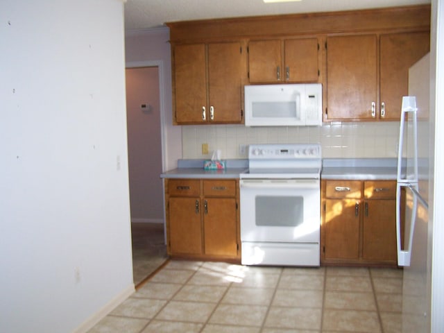 kitchen featuring white appliances, light tile patterned floors, and tasteful backsplash