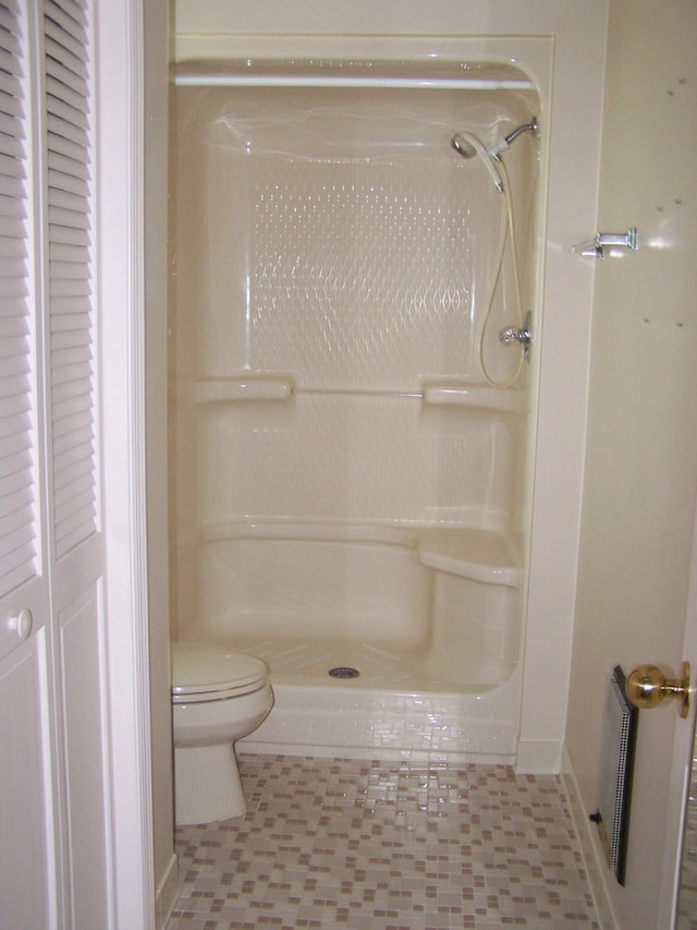 bathroom featuring toilet, a shower, and tile patterned floors