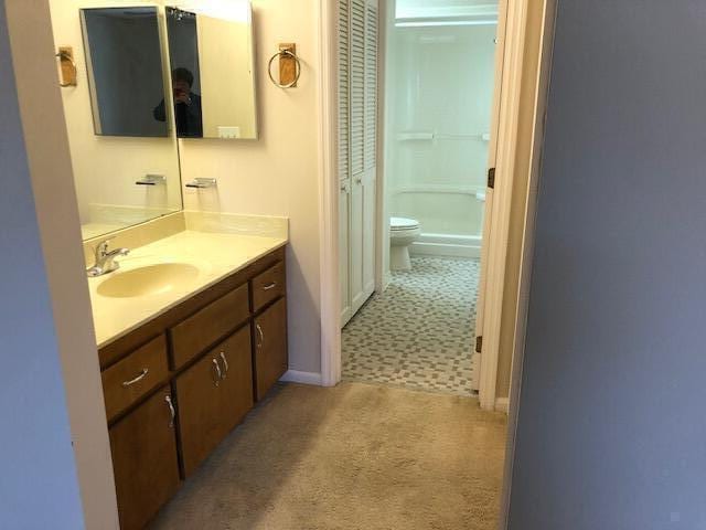 bathroom featuring toilet, a shower, and vanity