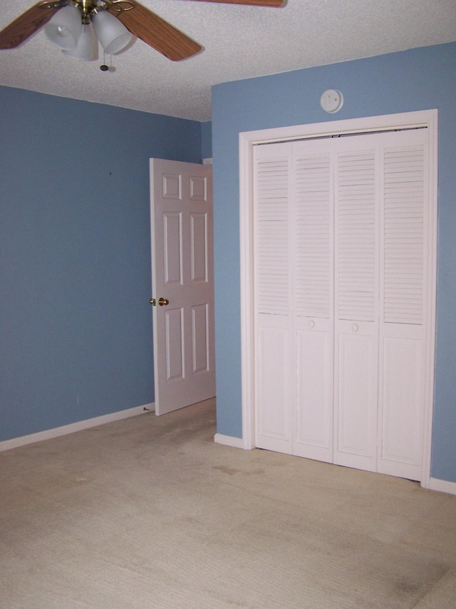 unfurnished bedroom featuring ceiling fan, a closet, light carpet, and a textured ceiling