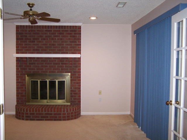 unfurnished living room featuring a textured ceiling, a brick fireplace, light carpet, and ceiling fan