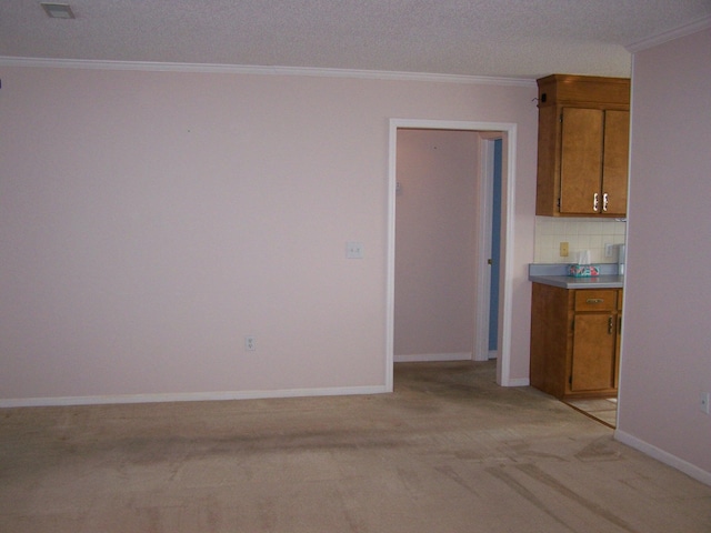 kitchen featuring light carpet, backsplash, crown molding, and a textured ceiling