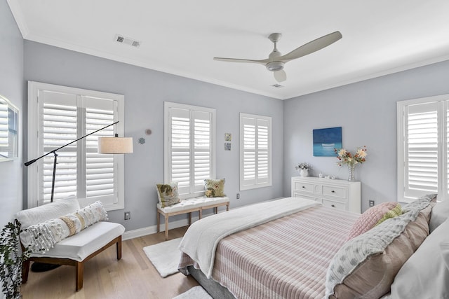 bedroom with baseboards, ornamental molding, a ceiling fan, visible vents, and wood finished floors