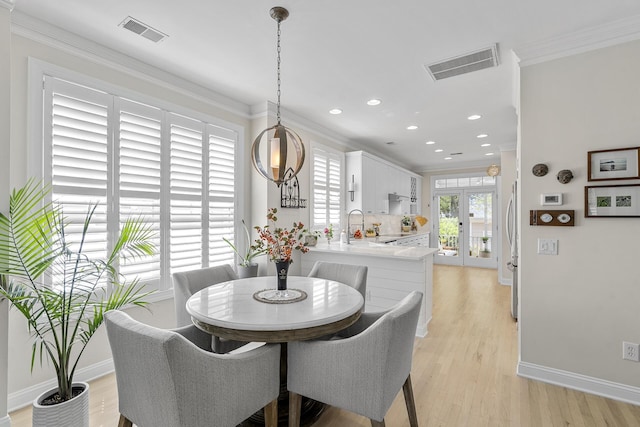 dining area featuring baseboards, visible vents, light wood-type flooring, and crown molding