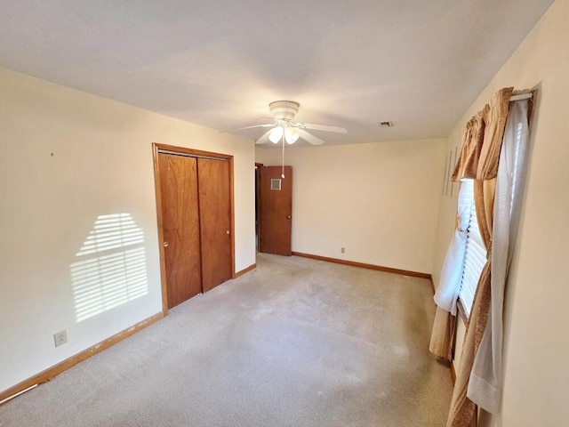 unfurnished bedroom with light carpet, ceiling fan, a closet, and baseboards