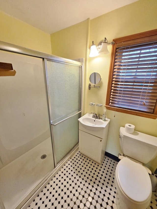 bathroom featuring toilet, a stall shower, vanity, and baseboards