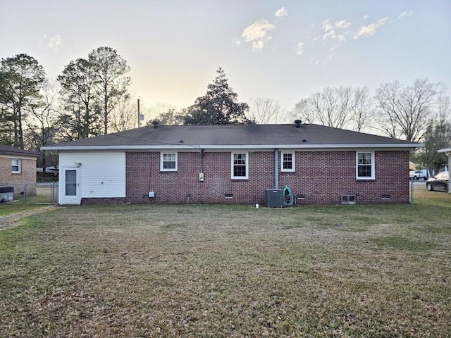 back of house featuring central AC, brick siding, fence, a yard, and crawl space