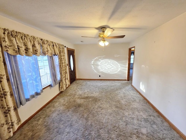 spare room featuring a textured ceiling, ceiling fan, carpet, and baseboards