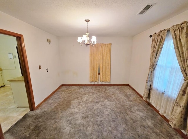 spare room featuring a chandelier, visible vents, carpet floors, and baseboards