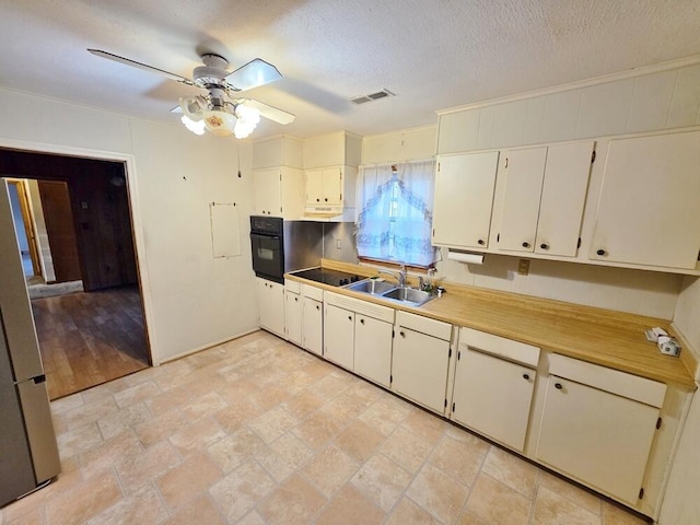 kitchen with visible vents, ceiling fan, a textured ceiling, a sink, and black oven