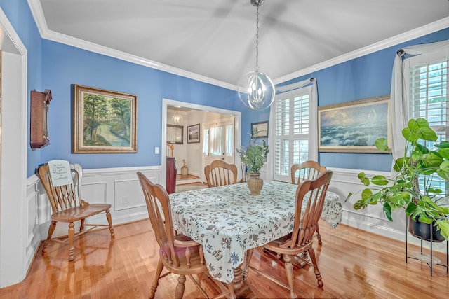 dining area with crown molding, light hardwood / wood-style floors, and a notable chandelier