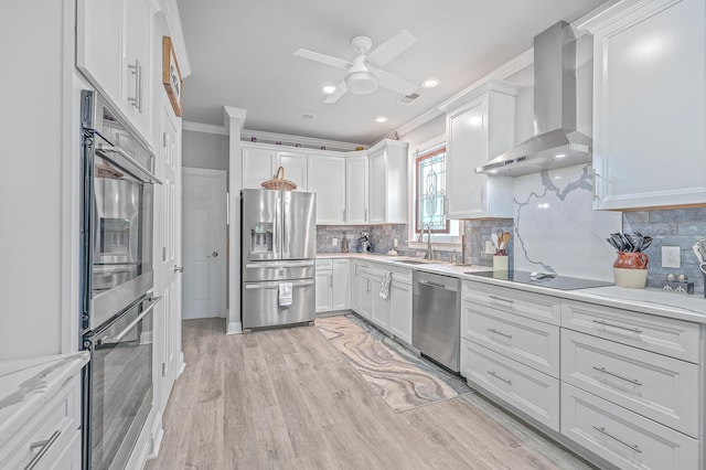 kitchen featuring white cabinets, stainless steel appliances, wall chimney exhaust hood, and sink