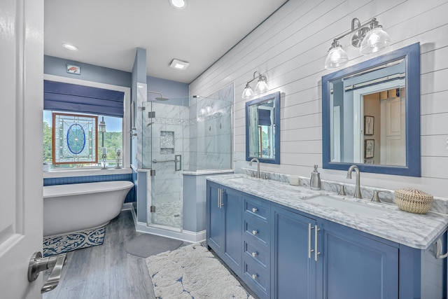 bathroom with hardwood / wood-style floors, vanity, wooden walls, and shower with separate bathtub