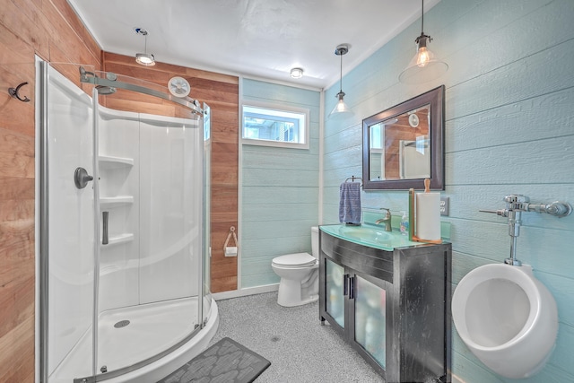 bathroom with an enclosed shower, vanity, wood walls, and toilet