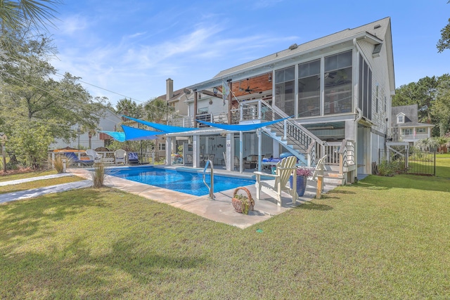 view of pool featuring ceiling fan, a patio area, a yard, and a sunroom