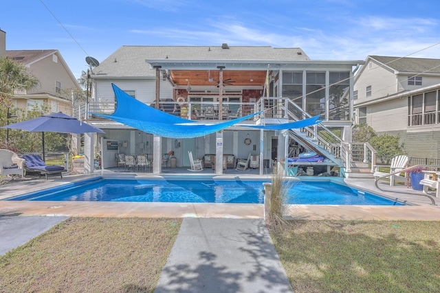 view of swimming pool featuring ceiling fan, a patio, a lawn, and a sunroom