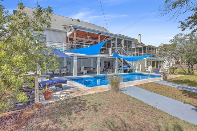 view of swimming pool with ceiling fan, a sunroom, a yard, and a patio