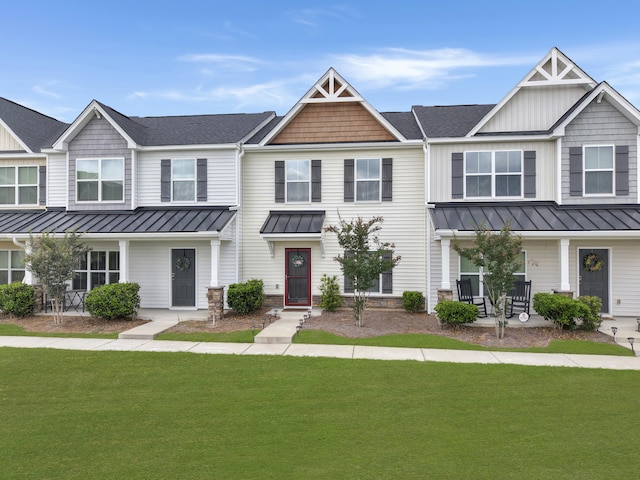 view of property featuring a standing seam roof, a porch, and a front yard