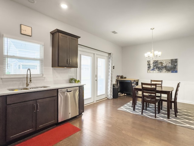 kitchen with dishwasher, a sink, dark brown cabinetry, dark wood-style floors, and light countertops
