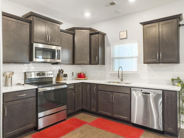kitchen with stainless steel appliances, a sink, light countertops, backsplash, and recessed lighting