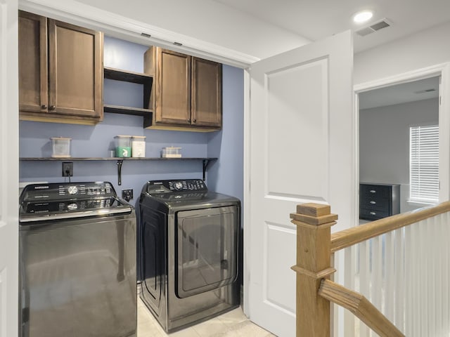 clothes washing area featuring cabinet space, washer and dryer, and light tile patterned flooring