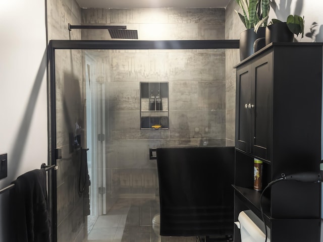 bathroom featuring toilet, an enclosed shower, and tile patterned flooring