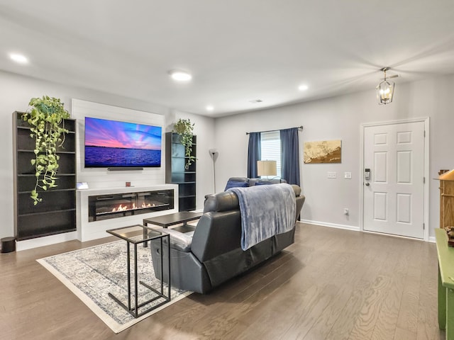 living area with wood finished floors, a glass covered fireplace, recessed lighting, and baseboards