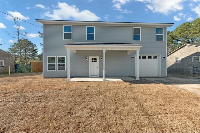 view of front of property featuring a garage, a front lawn, and a patio area