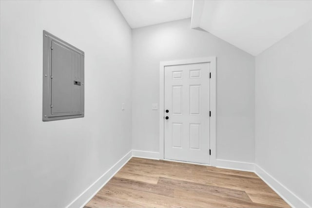 doorway to outside featuring lofted ceiling, light hardwood / wood-style floors, and electric panel