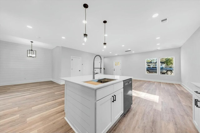 kitchen featuring sink, decorative light fixtures, white cabinets, an island with sink, and stainless steel dishwasher