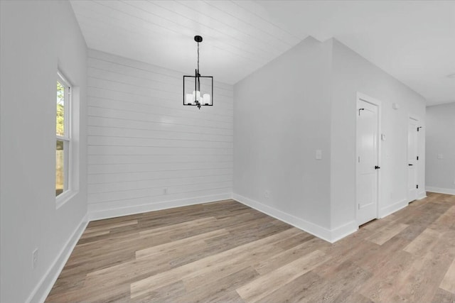 unfurnished dining area with light hardwood / wood-style floors and an inviting chandelier