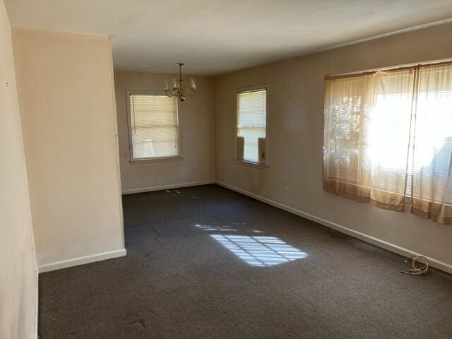 carpeted empty room with an inviting chandelier