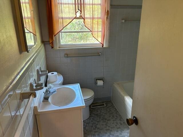 bathroom with vanity, a washtub, tile patterned floors, tile walls, and toilet